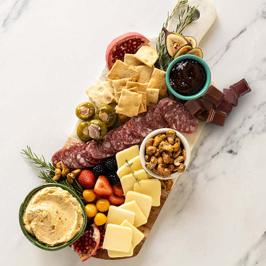 gourmet cheese and charcuterie gift box with assorted meats, cheeses, fruits, and snacks on a wooden board