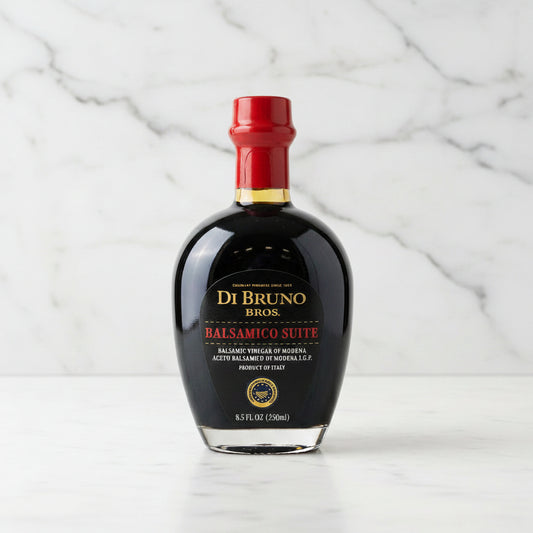 Bottle of Di Bruno Bros Balsamic Vinegar on a gray surface with a metallic background