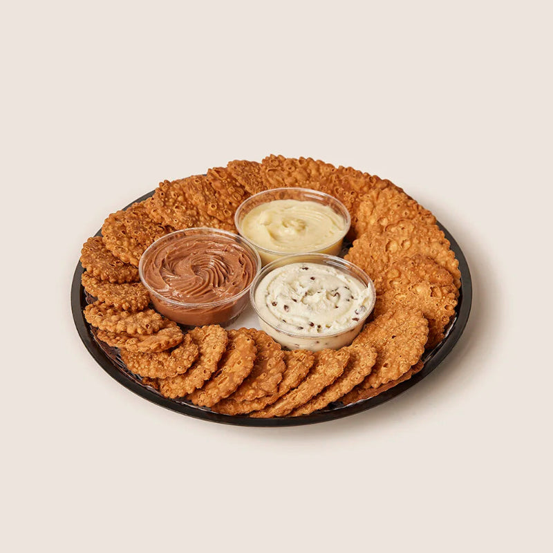 Round tray of cannoli crisps and three small cups of creams.