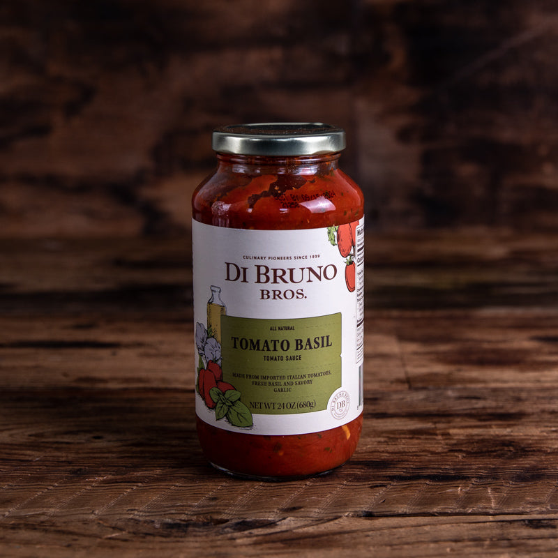 A jar of Di Bruno Bros. Tomato Basil pasta sauce on a wooden surface.