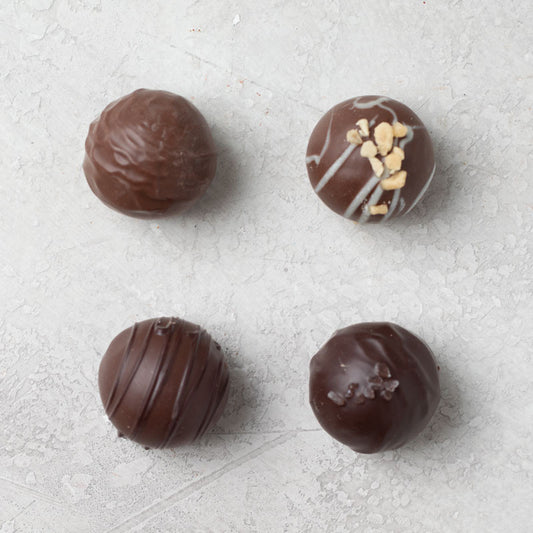 An assortment of Di Bruno Bros. chocolate truffles with different toppings such as nuts and caramel.