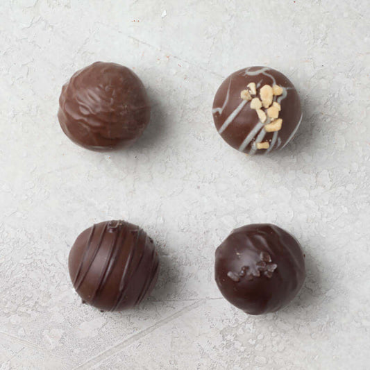 An assortment of Di Bruno Bros. chocolate truffles with different toppings such as nuts and caramel.