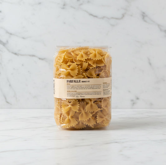 Bag of farfalle pasta on a white surface with a white box in the background