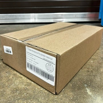 Cardboard box with shipping labels on a concrete floor in front of a metal storage unit.