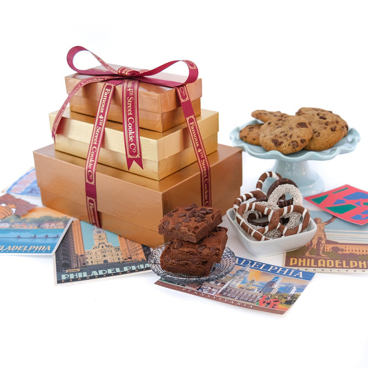 Gift box with a ribbon, cookies, brownies, and donuts on Philadelphia-themed magazines.