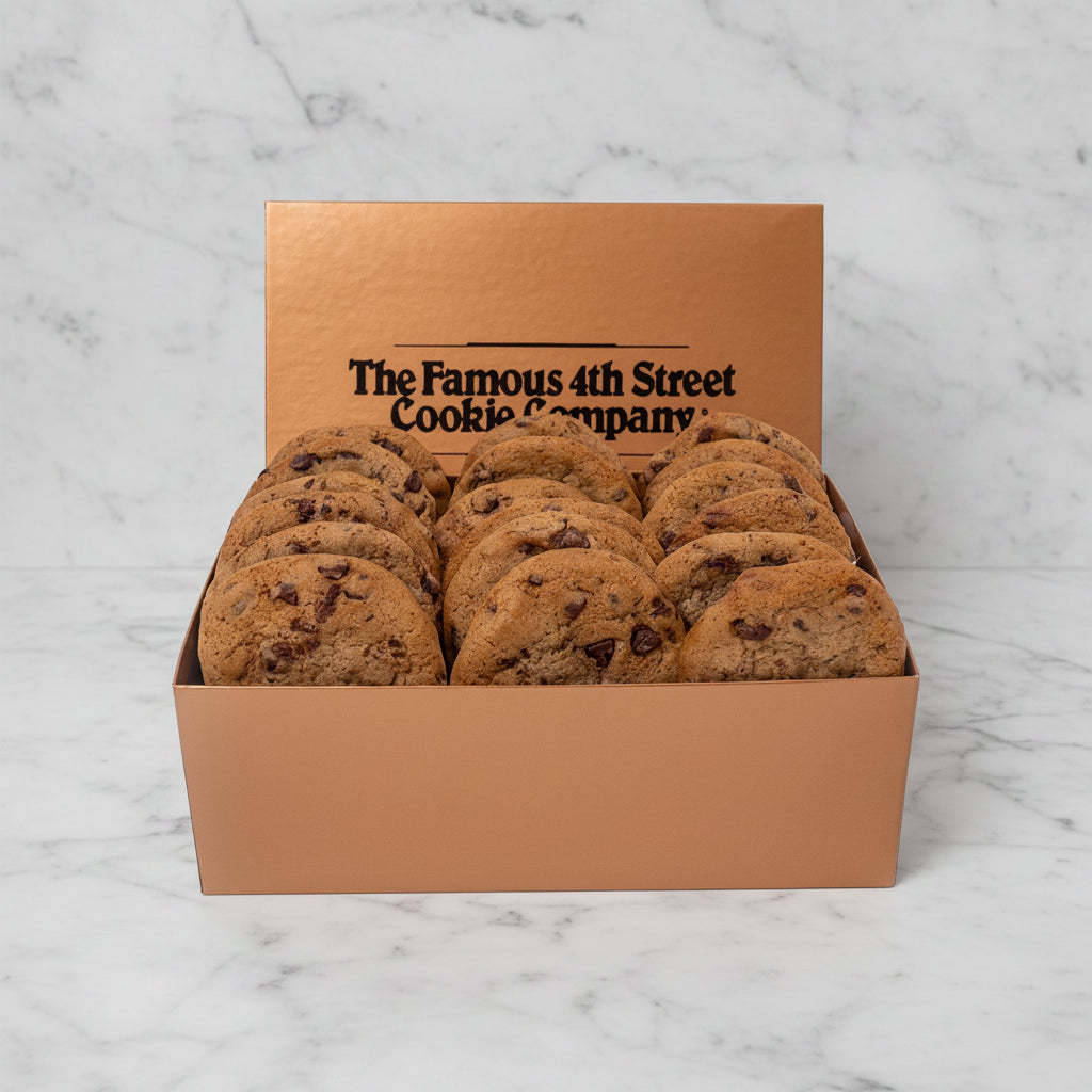 A box of chocolate chip cookies from The Famous 4th Street Cookie Company, shown in a metallic rose-gold colored box with the brand name printed on the inside lid, set against a white marble background.