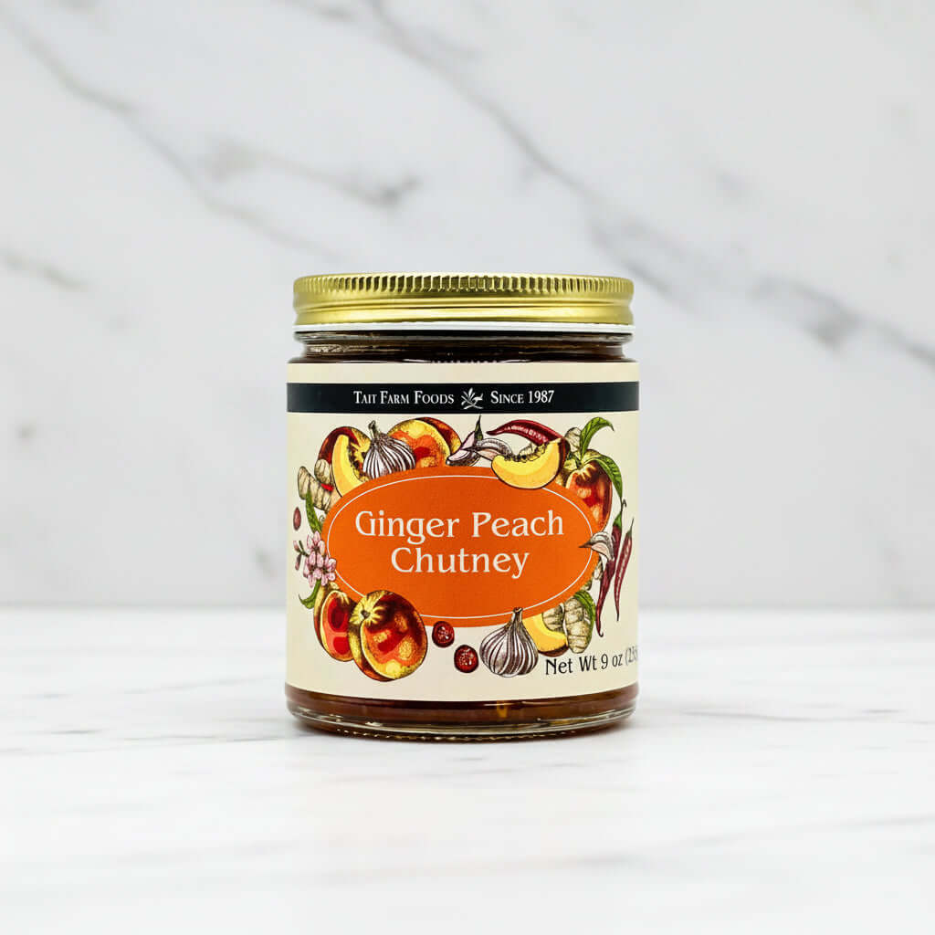 Ginger Peach Chutney jar with colorful label, showcasing ripe peaches and ginger, on a marble surface.
