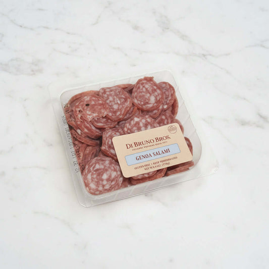 Packaged salami on a white surface with a brown background