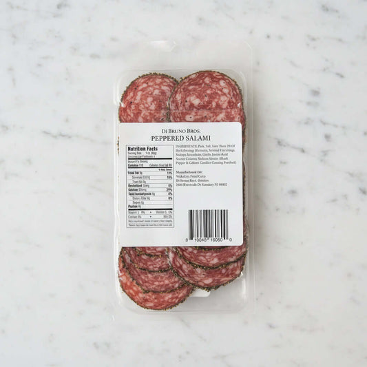 Packaged peppered salami with a label on a dark surface