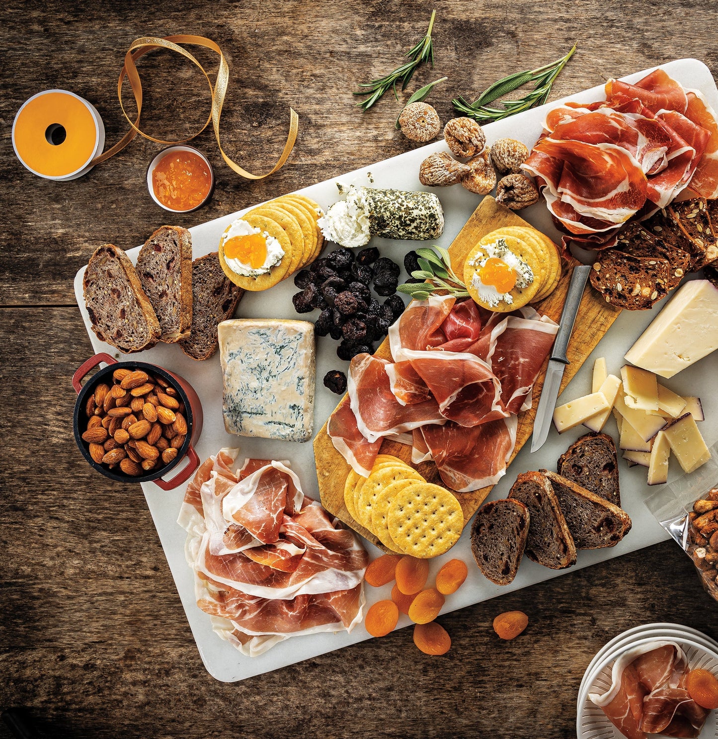 Assorted meats, cheeses, and crackers on a marble board with a wooden background