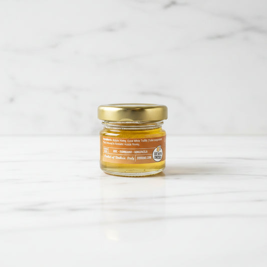 Small jar of honey with a gold lid on a dark surface