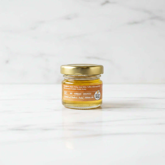 Small jar of honey with a gold lid on a dark surface