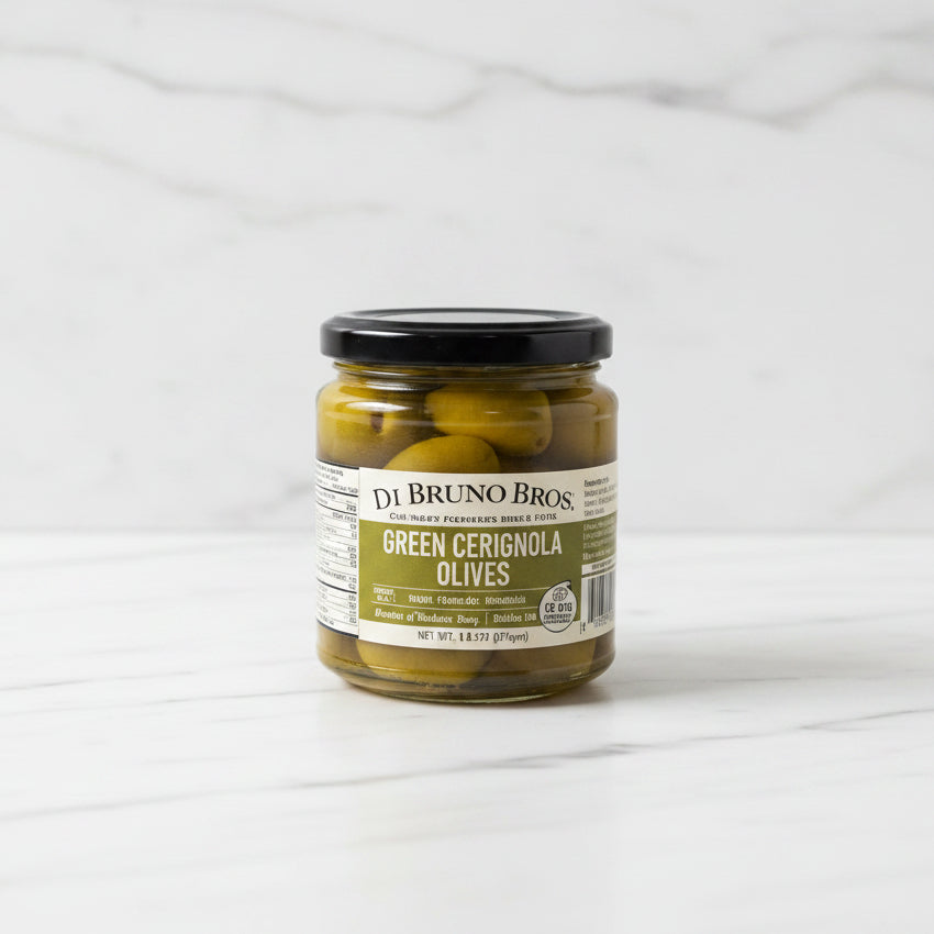 Jar of DeBruno Bros Green Cerignola Olives on a white surface with a blurred background