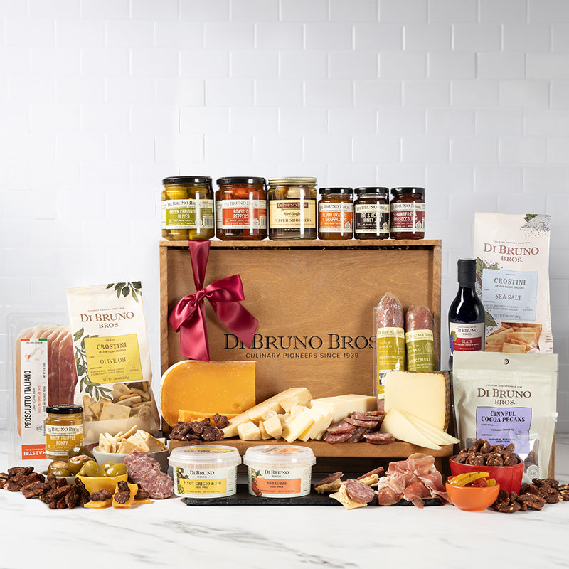 An extravagant assortment of gourmet cheeses, meats, chocolates, and crackers neatly arranged in a large Di Bruno Bros. wooden gift crate.