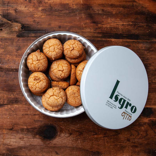 A tin of almond macaroon cookies on a wooden surface.
