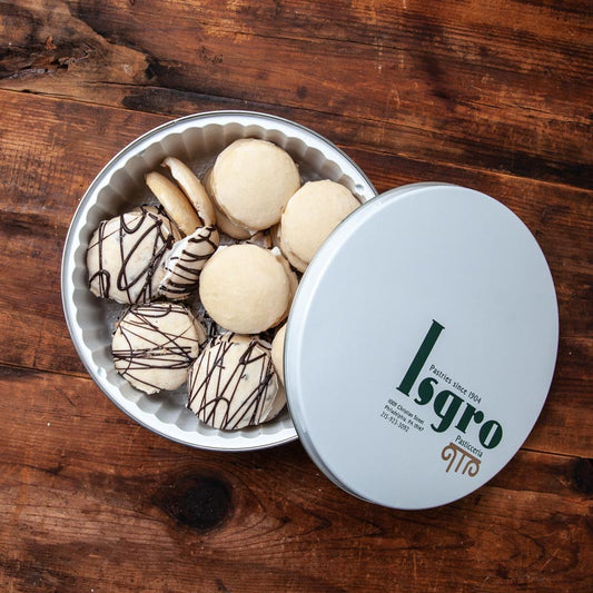 A tin of cookies with the brand 'Isgro' written on the lid, containing various types of cookies including Ricotta cookies, presented on a wooden surface.
