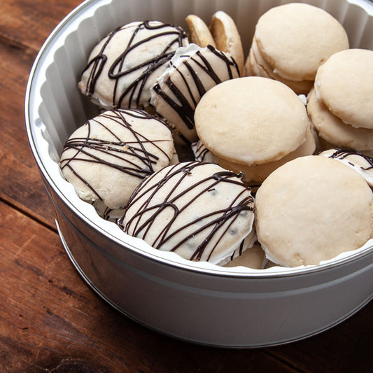 A tin of cookies with the brand 'Isgro' written on the lid, containing various types of cookies including Ricotta cookies, presented on a wooden surface.