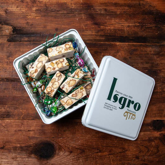 A tin of Isgro brand torrone, which is a type of nougat candy with nuts, presented in a square tin with the brand logo visible on the lid.