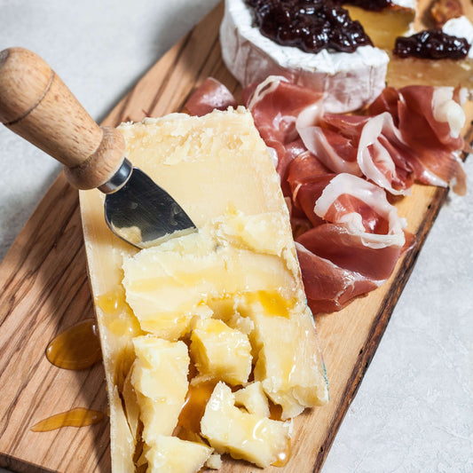 Piave DOP cheese on a wooden board with prosciutto and honey drizzle