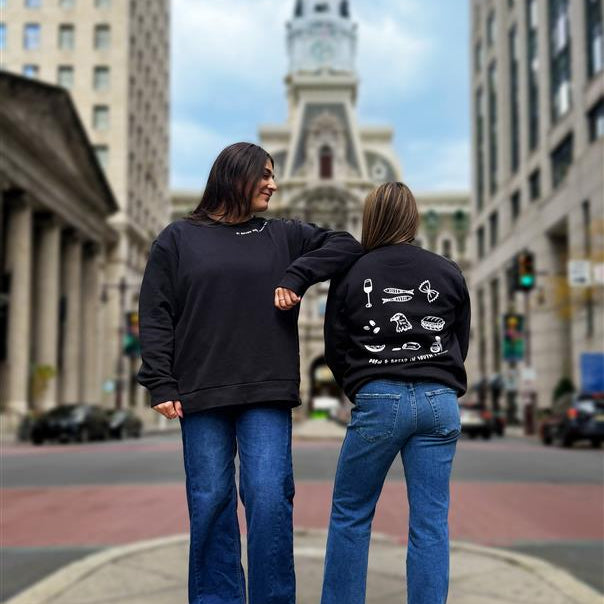 Two people standing on a city street with a prominent clock tower in the background.