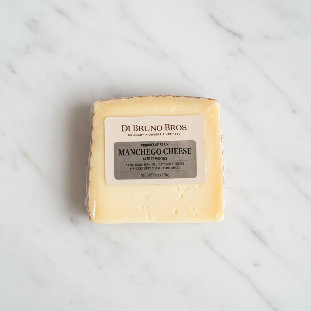 Block of Manchego cheese with Di Bruno Bros label on a dark surface