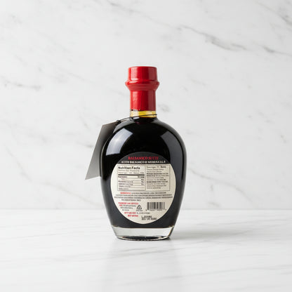 Bottle of Di Bruno Bros. Balsamic Vinegar on a metallic surface with a blurred background