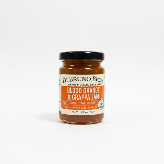 Jar of Di Bruno Bros Blood Orange & Grappa Jam on a dark surface with a white background