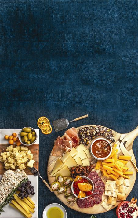 Assorted Di Bruno Bros. charcuterie board with meats, cheeses, and fruits on a dark blue background
