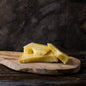 Sliced pieces of cheese on a wooden cutting board, with a rustic background.