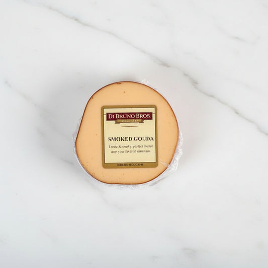A round piece of smoked gouda cheese with a label in the center displaying the cheese name and brand.