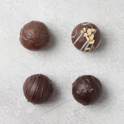 An assortment of Di Bruno Bros. chocolate truffles with different toppings such as nuts and caramel.