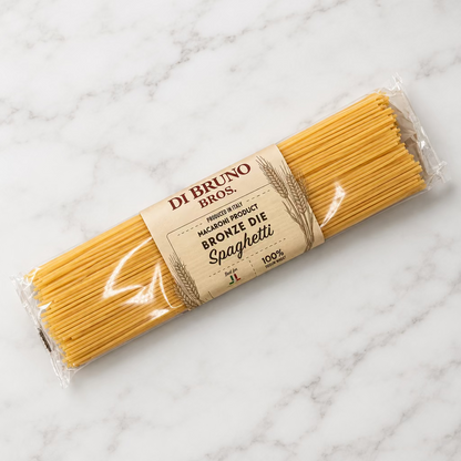 A package of Di Bruno Bros. Brownie Die Spaghetti, featuring uncooked spaghetti noodles in clear plastic wrapping with a tan paper label, placed on a white surface.