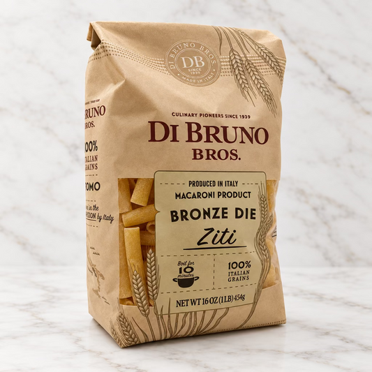 A 16 oz bag of Di Bruno Bros. Bronze Die Ziti pasta, featuring a tan paper bag with a clear window showing the yellow-beige penne pasta inside, set against a plain white background.