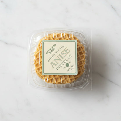 Packaged anise pizzelle on a reflective surface with a neutral background