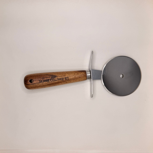 A pizza cutter with a brown wooden handle and a silver metal blade, resting on a white marble countertop