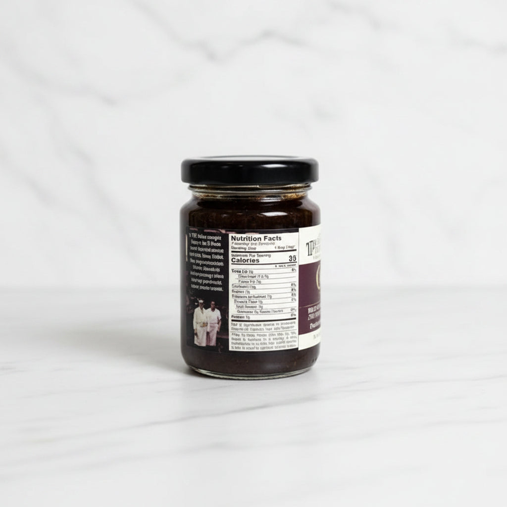 Small jar with a label on a dark surface and tiled wall background