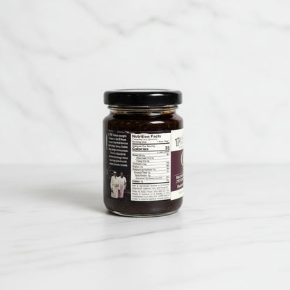 Small jar with a label on a dark surface and tiled wall background