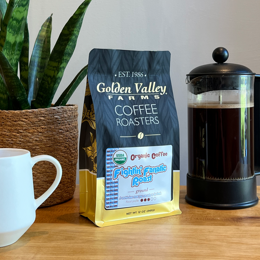 Fightin' Fanatic Roast Organic Coffee, 12-Ounce Bag on a wooden table with a cup and French press.