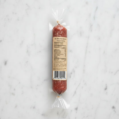 Packaged salami with a label on a marble surface