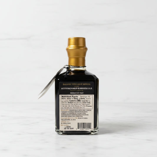 Bottle of Balsamic Vinegar of Modena on a reflective surface with a neutral background