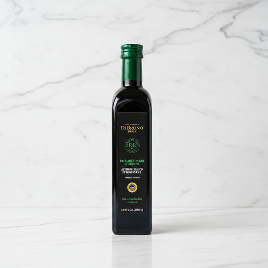 Bottle of DeBruno olive oil on a reflective surface with a blurred background