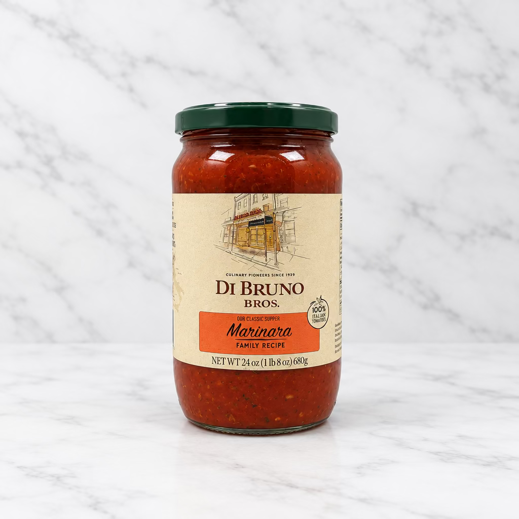 A glass jar of Di Bruno Bros. Marinara sauce with a cream label and a dark green lid, set against a white studio backdrop.