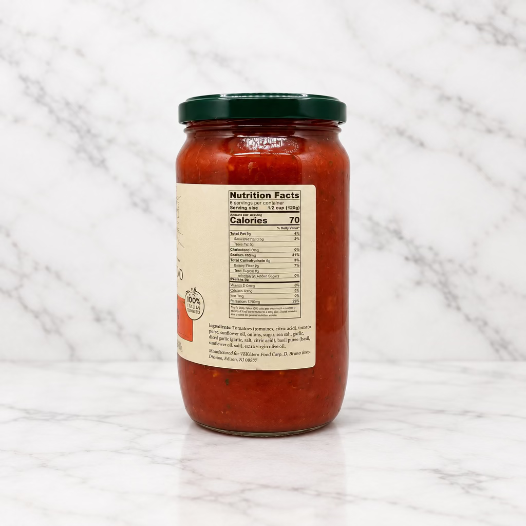 A glass jar of pasta sauce with a dark green lid and a beige nutrition facts label, shown from the back on a white studio background.
