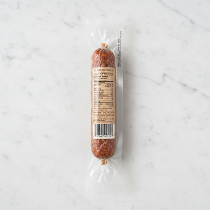 Packaged salami with a label on a dark surface