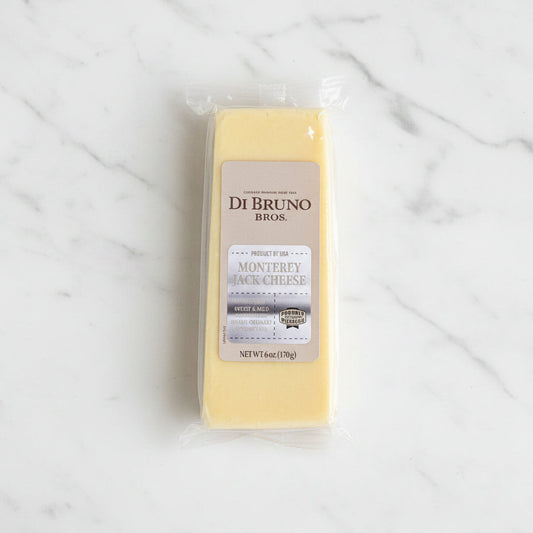 Block of cheese with a Di Bruno Bros label on a dark surface