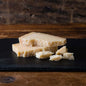 A variety of Parmigiano Reggiano cheese on a black cheese board.