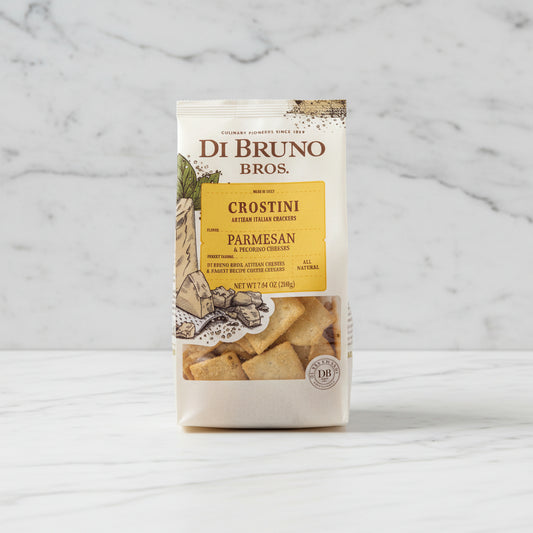Di Bruno Bros. Parmesan Crostini packaging on a dark surface with a blurred background