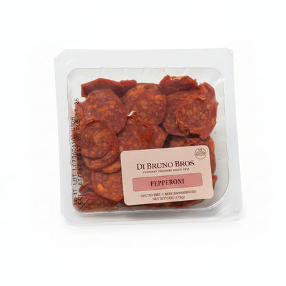 Packaged pepperoni slices with a label on a gray surface