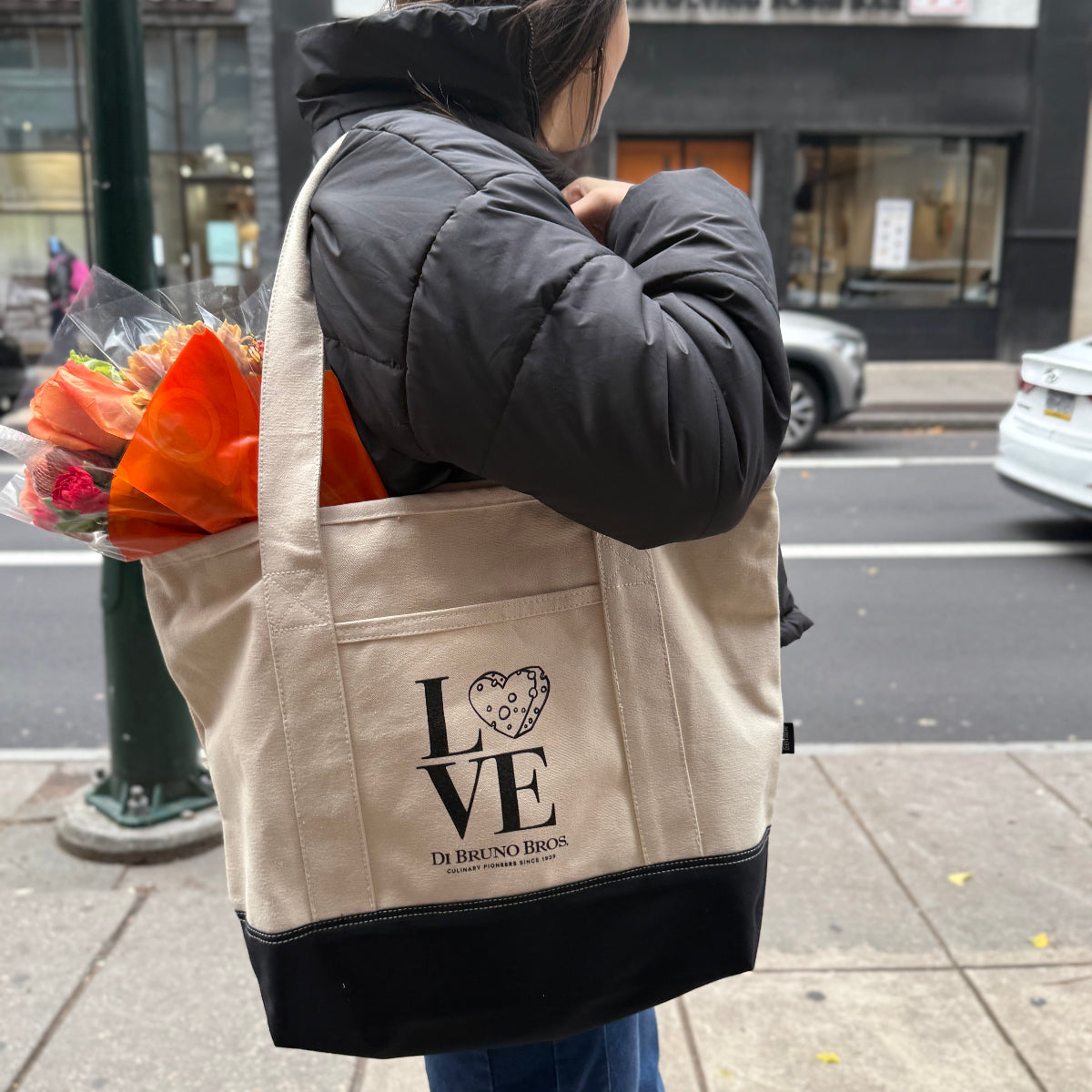 Person holding a tote bag with 'LOVE' design on a city street