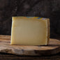 A wedge of Piave cheese on a wooden cheese board.